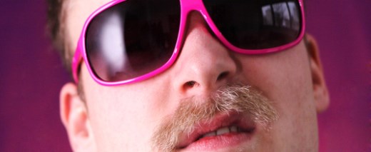 Mann mit Schnurbart und rosa Brille guckt provokativ