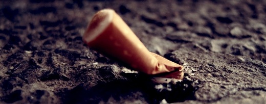 Nahaufnahme einer ausgedrückten Zigarettenkippe auf Asphalt