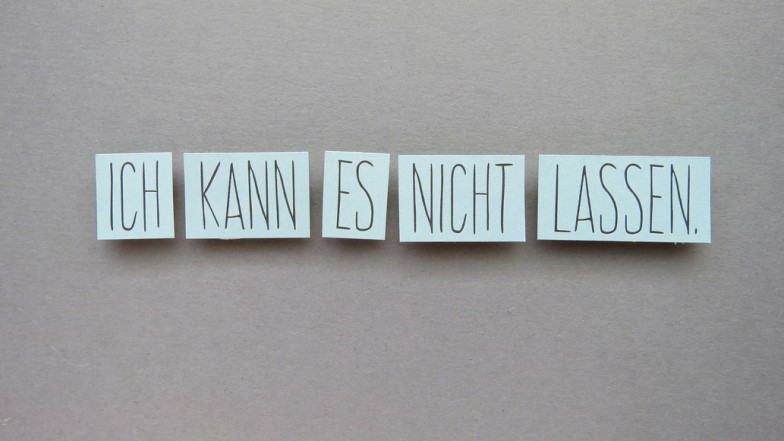 Die Wörter "Ich", "kann", "es", "nicht" und "lassen" vor grauem Hintergrund.