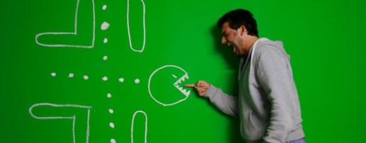 Mann hält Finger in das Maul von Pacman, der auf einer Wand gemalt ist und schreit