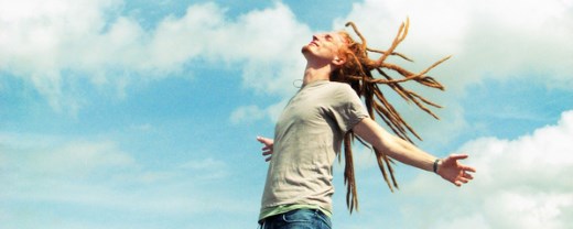 Mann mit Rastahaaren genießt die frische Luft vor blauem Himmel