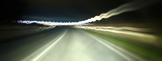 Langzeitbelichtung durch Frontscheibe Auto auf dunkle Straße mit Lichtern