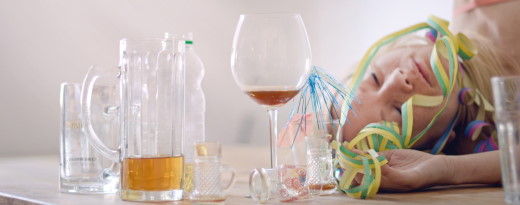 Halb leere Gläser auf Tisch, Frau schläft im Hintergrund